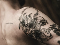 Татуировка в виде трех лилий на плече