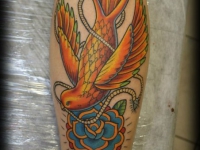 Татуировка птица с цветком на икре