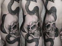 Татуировка на боку и бедре змея обвивающая череп