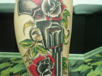 Татуировка револьвер с розами на голени