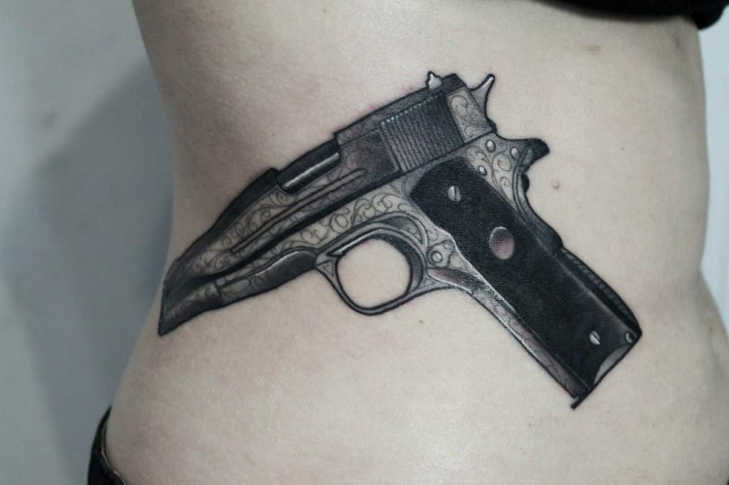 Художественная татуировка «Пистолет». Мастер — Саша Новик. Расположение — бок. По идее клиента.