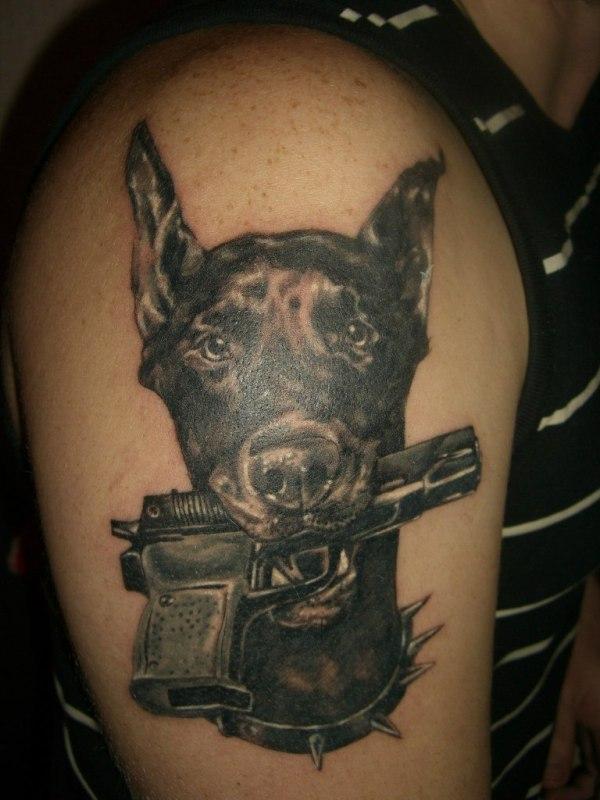 Татуировка собака с пистолетом в зубах на плече
